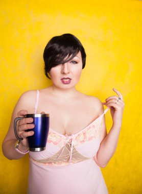 Stüdyoda sarı arka planda mavi termosu olan çekici bir kız.