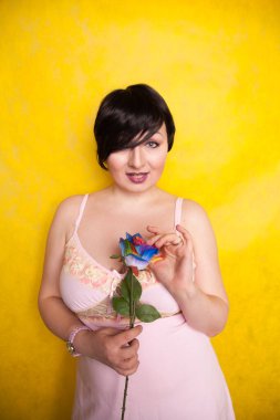 Sarı arka planda suni çiçekli güzel bir kadın.