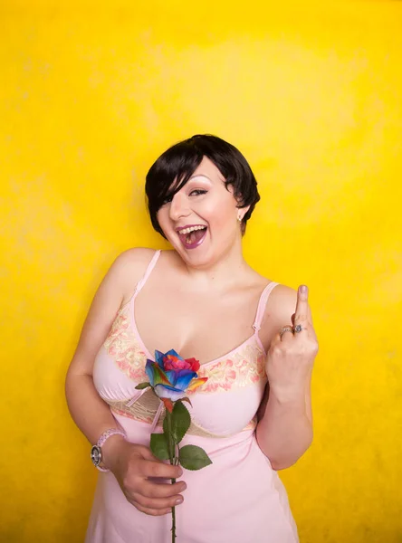 Beautiful woman with artificial flower on yellow background — ストック写真