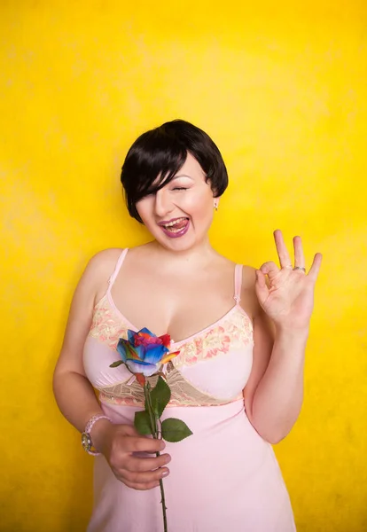 Hermosa mujer con flor artificial sobre fondo amarillo —  Fotos de Stock