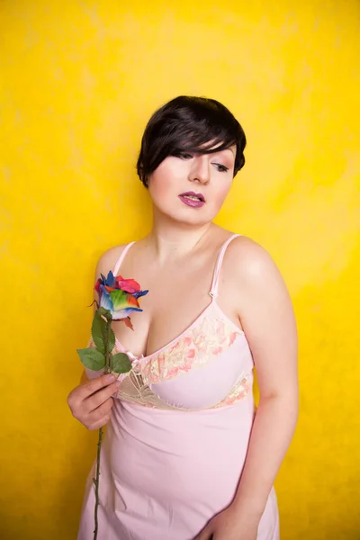 Hermosa mujer con flor artificial sobre fondo amarillo —  Fotos de Stock