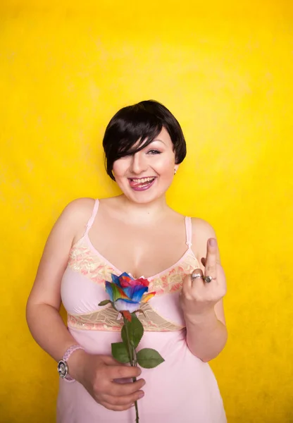 Gyönyörű nő mesterséges virág sárga háttér — Stock Fotó