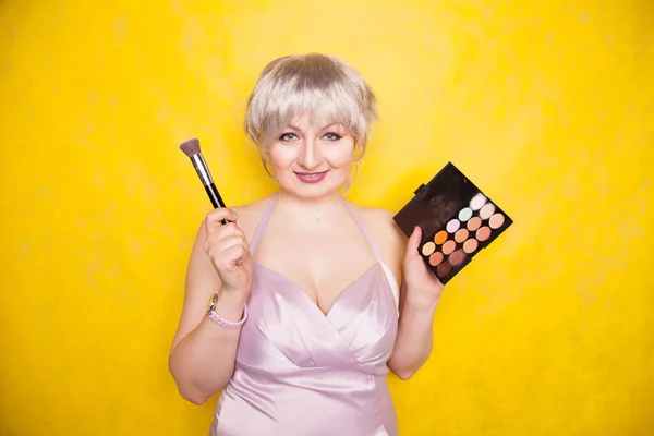 Happy plus size woman having fun with make-up palette set and brush. Professional multicolor eyeshadow face corrector palette. — Stock Photo, Image