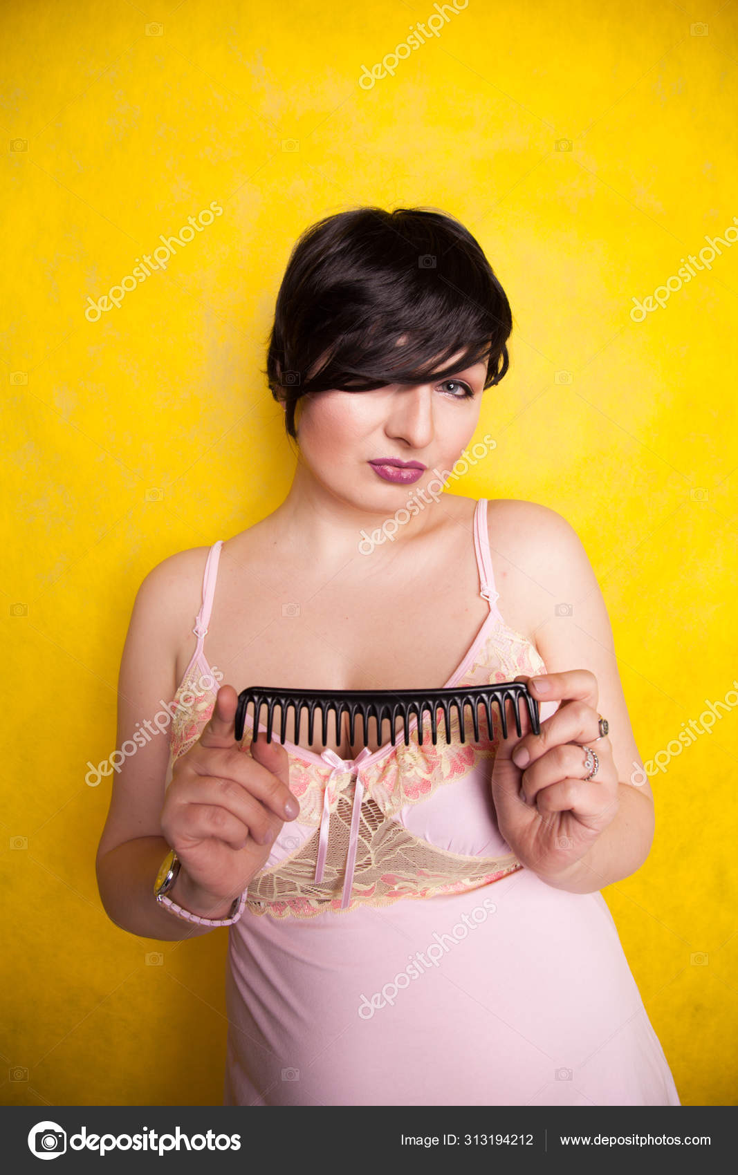Secador de cabelo preto na mão de uma mulher em um fundo amarelo