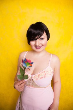 Sarı arka planda suni çiçekli güzel bir kadın.