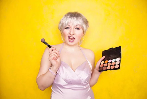 Happy plus size woman having fun with make-up palette set and brush. Professional multicolor eyeshadow face corrector palette. — Stock Photo, Image
