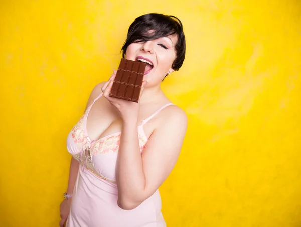 Uma bela mulher plus-size flerta com uma mordida de chocolate escuro . — Fotografia de Stock