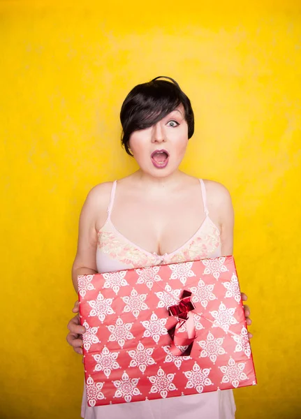 リボンで手に大きな贈り物を保持不幸な女性。大人女の子とともに赤-黄色のスタジオの背景. — ストック写真
