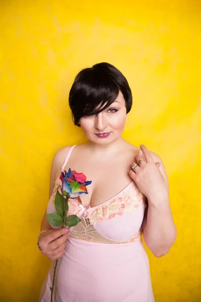 Hermosa mujer con flor artificial sobre fondo amarillo —  Fotos de Stock