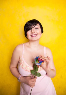 Sarı arka planda suni çiçekli güzel bir kadın.