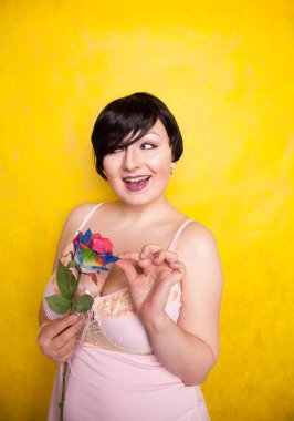 Sarı arka planda suni çiçekli güzel bir kadın.