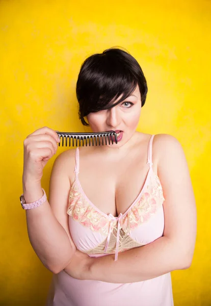 Brunette with Short Hair standing with comb on yellow background alone — ストック写真