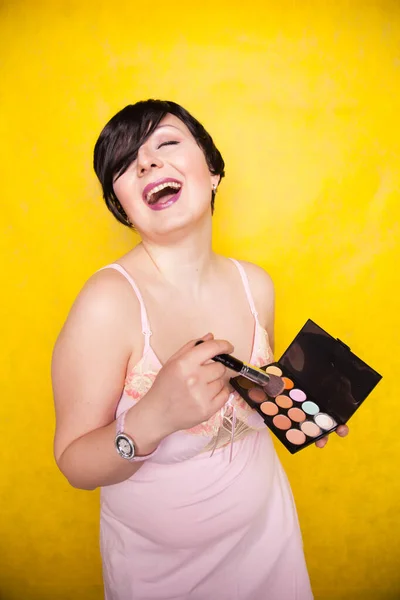 Feliz mulher plus size se divertindo com conjunto de paleta de maquiagem e escova. Paleta multicolorida profissional do corretor da cara da sombra . — Fotografia de Stock