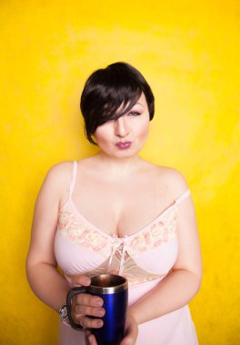 Stüdyoda sarı arka planda mavi termosu olan çekici bir kız.