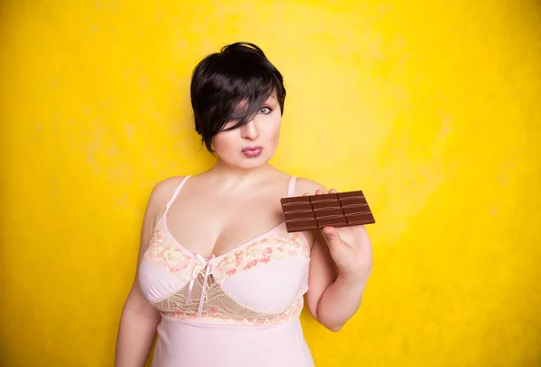 Piękna kobieta w rozmiarze plus flirtuje z gryzieniem ciemnej czekolady. — Zdjęcie stockowe