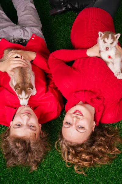 Feliz mamá y el hijo posan en la hierba verde con dos cachorros husky lindo —  Fotos de Stock