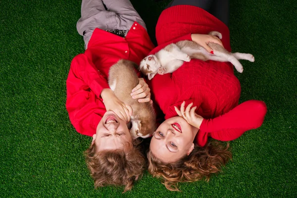 Bonne maman et son fils posent sur l'herbe verte avec deux petits chiots husky mignons — Photo
