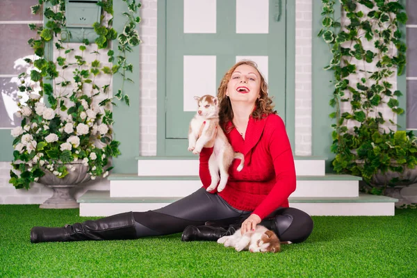 Bastante caucásico más mujer de tamaño en suéter rojo con dos cachorros husky lindo en hierba verde — Foto de Stock