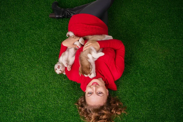 Jolie caucasien plus taille femme en pull rouge avec deux chiots husky mignon sur herbe verte — Photo