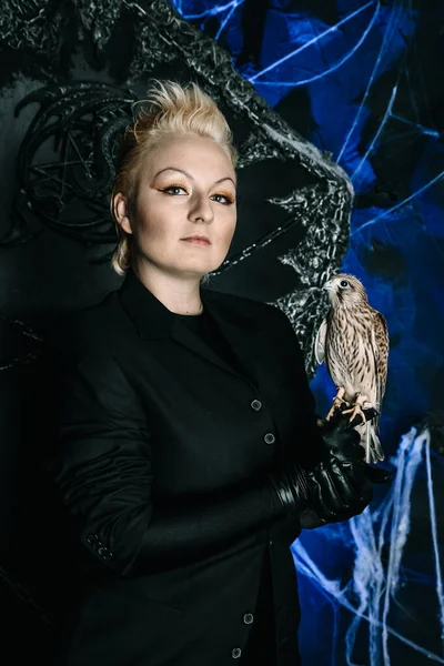 Photo of a female witch queen holding bird and sitting on a gothic scary black throne — Stock Photo, Image