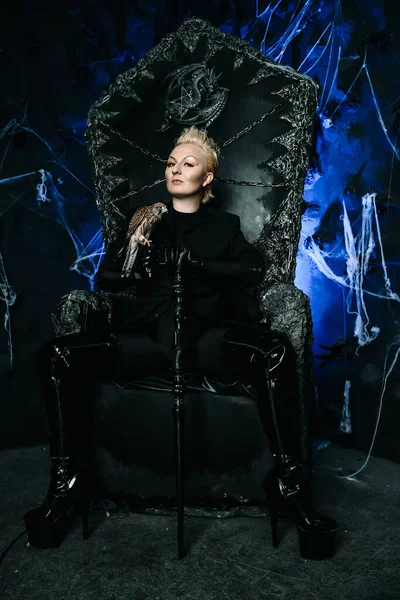 새를들고 고딕처럼 무섭게 생긴 검은 왕좌에 앉아 있는 한 여성 마녀의 사진 — 스톡 사진