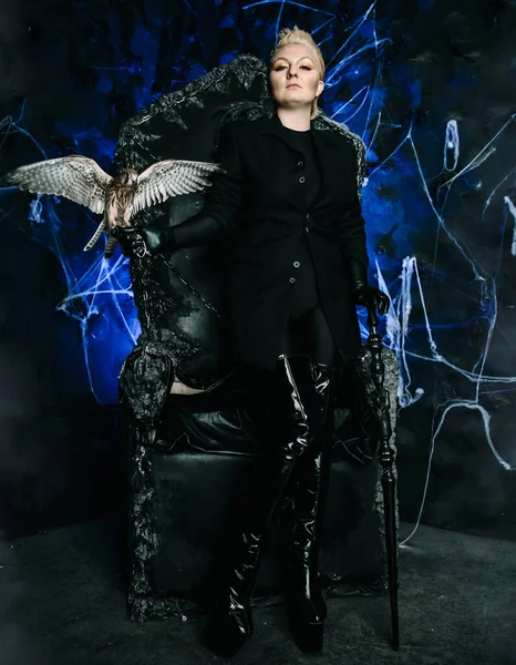 새를들고 고딕처럼 무섭게 생긴 검은 왕좌에 앉아 있는 한 여성 마녀의 사진 — 스톡 사진