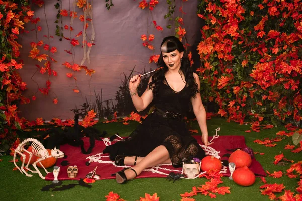 Slim fashion halloween girl with black hair in lace gothic pin up dress posing in the autumn background with fall leaves — Stock Photo, Image