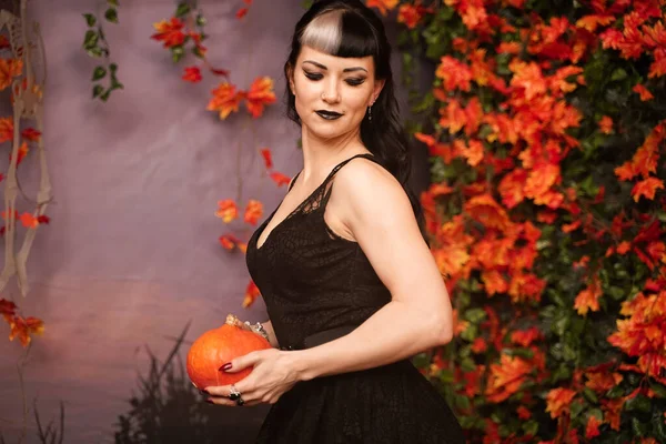 Slim moda Halloween ragazza con i capelli neri in pizzo gotico pin up vestito in posa in autunno con foglie autunnali — Foto Stock