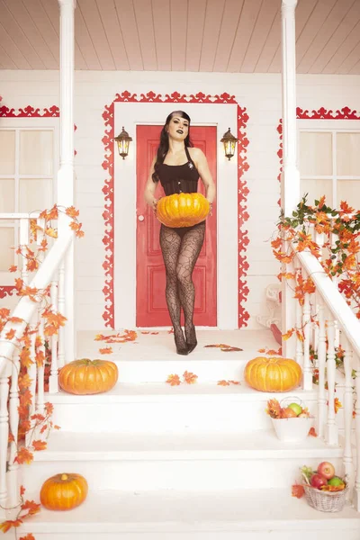 Hot sexy woman come for trick or treat halloween night. Gothic vampire girl on white porch of decorated autumn house. — 스톡 사진