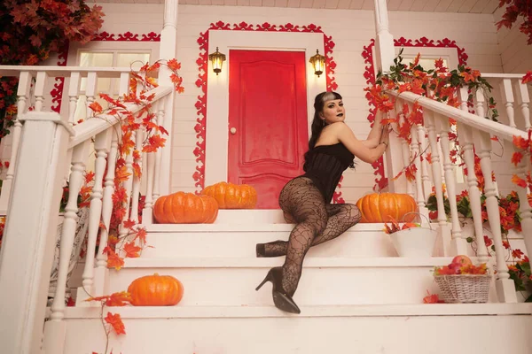 Hot sexy Frau kommen für Trick oder behandeln halloween night. Gothic Vampir Mädchen auf der weißen Veranda des dekorierten Herbst Haus. — Stockfoto