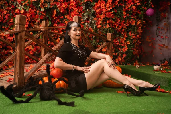 Сексуальная и привлекательная брюнетка ведьма осенью красочный парк с оранжевыми и красными листьями позирует с тыквами — стоковое фото
