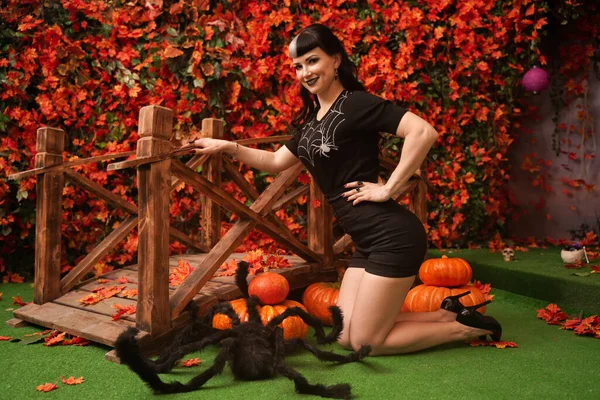 Сексуальная и привлекательная брюнетка ведьма осенью красочный парк с оранжевыми и красными листьями позирует с тыквами — стоковое фото