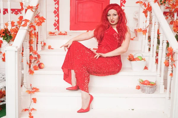 Joven mujer gordita con estilo vistiendo maxi vestido rojo en el porche de su casa blanca. Moda de otoño, aspecto elegante. Modelo de tamaño más . — Foto de Stock
