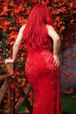 Güz parkında kırmızı, uzun gece elbisesi içinde güzel, tombul bir kız. tam boy gövde.