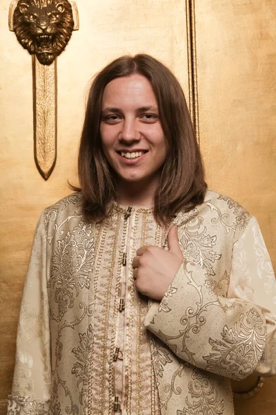 Charmante verlegen jonge tiener kerel in een middeleeuwse stijl gouden pak in een foto Studio is klaar om te gaan naar een feest — Stockfoto