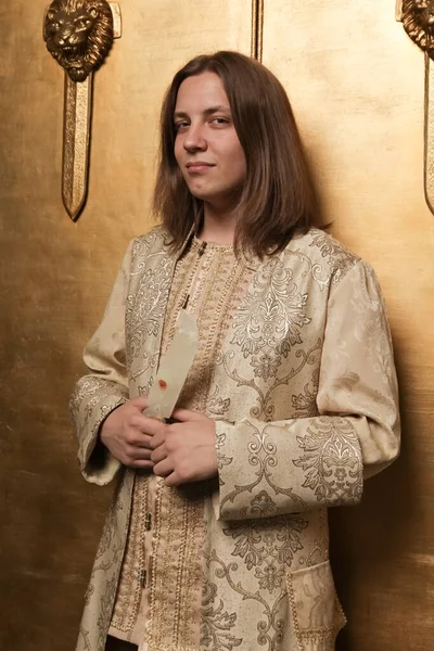 Charmante schüchterne junge Teenager in einem mittelalterlichen goldenen Anzug in einem Fotostudio ist bereit, auf eine Party zu gehen — Stockfoto