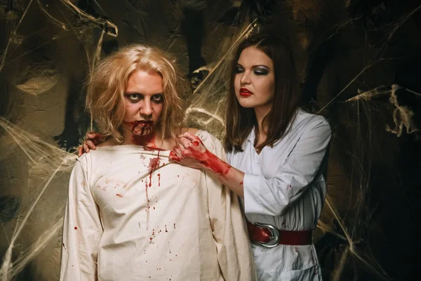 Portrét krásného páru v zakrvácených lékařských kostýmech s halloweenským make-upem. Zastřelen ve studiu. — Stock fotografie