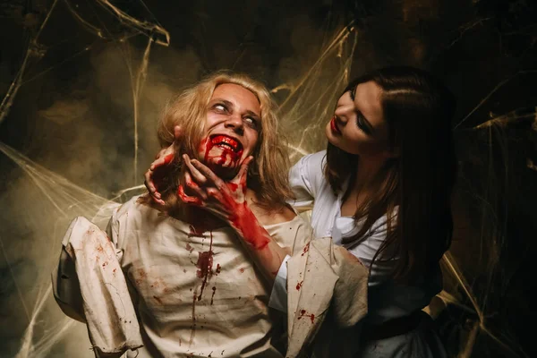 Portrait of a beautiful couple in medical bloody costumes with halloween style make-up. Shot in a studio. — Stock Photo, Image