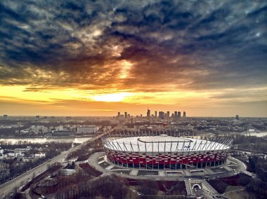 Varşova gökdelen ile modern şehir ve Pge Narodowy Ulusal Stadyumu güzel panoramik hava dron görünümüne (Lehçe: Stadion Narodowy) dramatik bir gün batımı arka planı