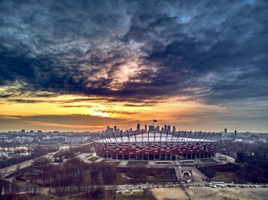 Varşova gökdelen ile modern şehir ve Pge Narodowy Ulusal Stadyumu güzel panoramik hava dron görünümüne (Lehçe: Stadion Narodowy) dramatik bir gün batımı arka planı