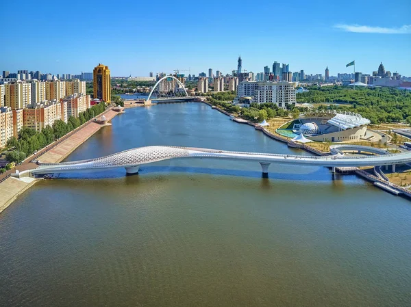 Nur-sultan, kasachstan - 30. juli: wunderschöner panorama-drohnenblick auf ishim flußdamm??? Nur-Sultan oder Nursultan (astana) Stadtzentrum mit Wolkenkratzern und moderner Fußgängerbrücke — Stockfoto