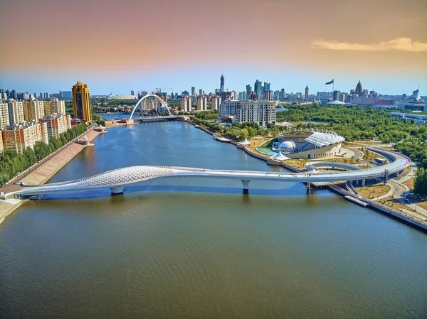 Nur-Sultan, Kazakistan - 30 Temmuz: Ishim Nehri Embankment 'e güzel panoramik hava aracı manzarası Gökdelenleri ve modern yaya köprüsü olan Nur-Sultan (Astana) şehir merkezi — Stok fotoğraf