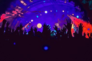 Soyut bulanık atmosfer: açık hava müzik festivali konserinden hoşlanan mutlu insanlar, el kaldırdılar ve zevk alkışladılar, aktif gece hayatı konsepti, büyük sahnede ışık ve gölge oyunu