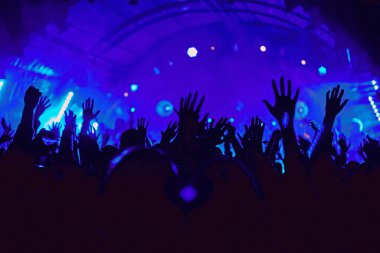 Soyut bulanık atmosfer: açık hava müzik festivali konserinden hoşlanan mutlu insanlar, el kaldırdılar ve zevk alkışladılar, aktif gece hayatı konsepti, büyük sahnede ışık ve gölge oyunu
