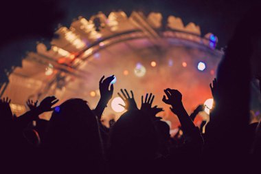 Soyut bulanık atmosfer: açık hava müzik festivali konserinden hoşlanan mutlu insanlar, el kaldırdılar ve zevk alkışladılar, aktif gece hayatı konsepti, büyük sahnede ışık ve gölge oyunu