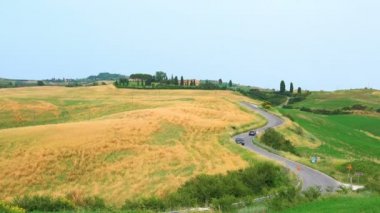 Güneşli gün S eğimli yolda Valdorcia İtalya ile tepelik Toskana buğday sahasında peyzaj