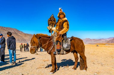 Ulgii, Moğolistan - 6 Ekim 2018: altın kartal Festivali. Altın kartal Hunter içinde geleneksel kıyafetler, Fox Kürk ile onun yandan Ulgii Moğolistan'da rekabet sitesinde de kartal
