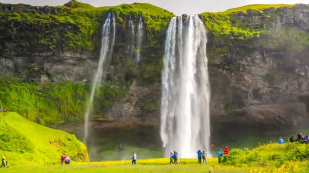 VIK, Island - 15 července 2018: Vodopádů Seljalandfoss, turisté mohou chodit do jeskyně za ním. Časová prodleva 4k Dci