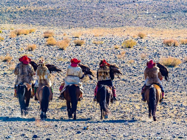 Mongolian Golden Eagle Hunter in traditional clothing riding on horseback to the Golden Eagle Hunter Festival competition site at Ugii in western Mongolia