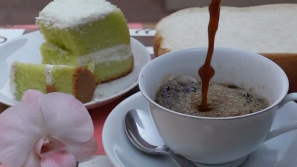 将咖啡倒进一个白色的杯子里 上面有蛋糕和慢动作中的切片面包 — 图库视频影像